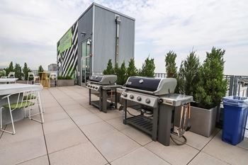 A barbecue grill is set up on a patio in front of a building.